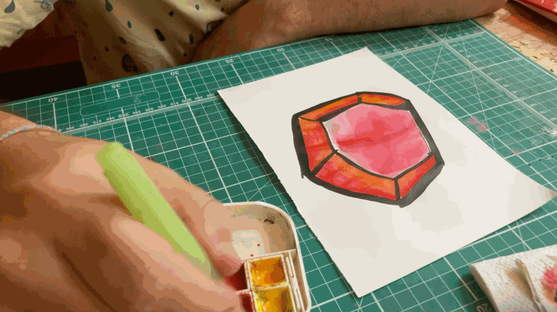a hand coloring a drawing with watercolour