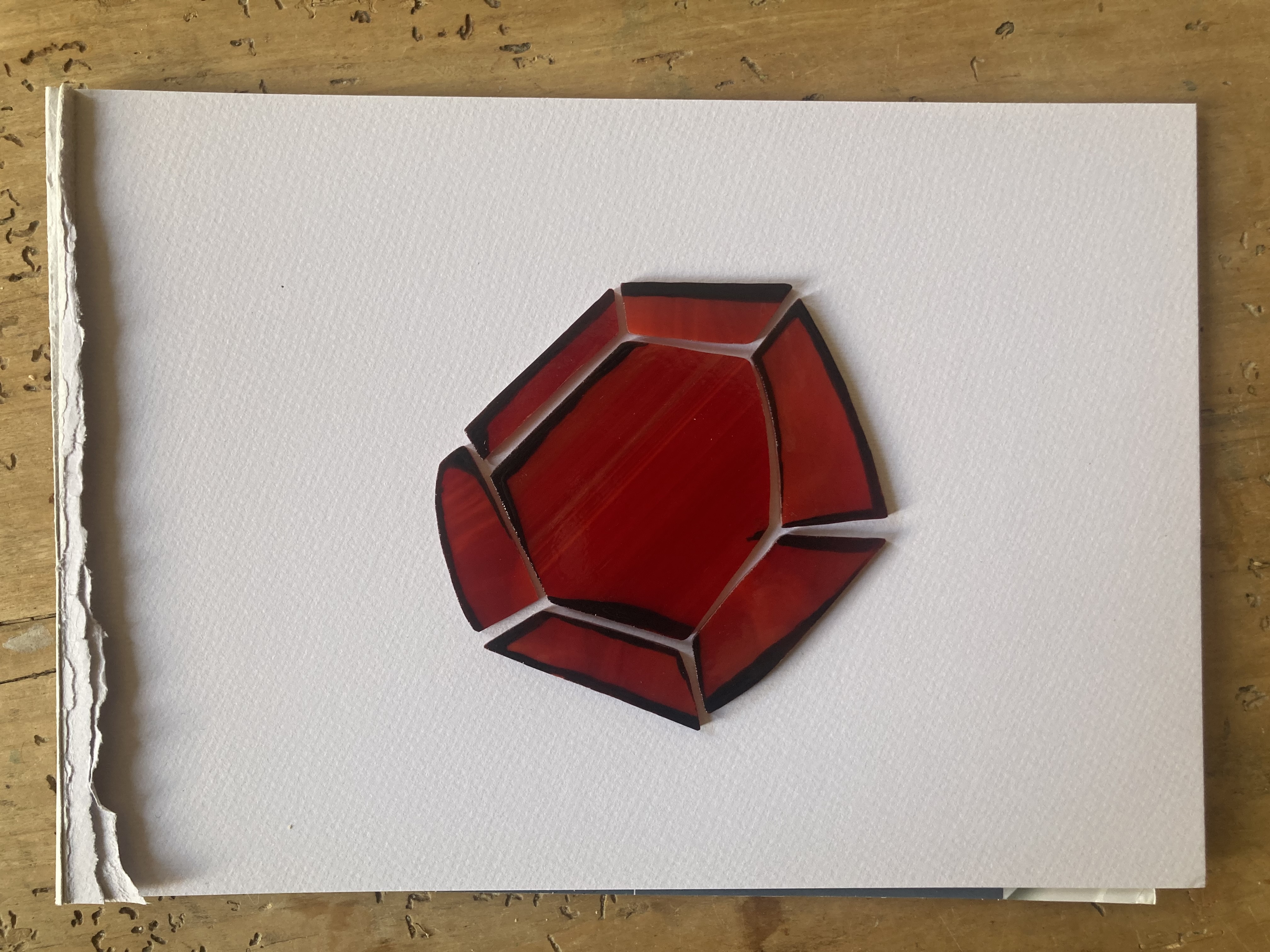 red glass pieces painted, resting on a white paper